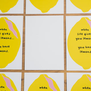 Postkarte mit dem Spruch ‘When life gives you lemons… you have lemons’, illustriert mit einer großen gelben Zitrone und rosa Akzenten, arrangiert mit weißer Rückseite, von Typealive.