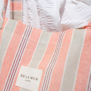 Stofftasche Everyday Bag M im Muster Coral Stripes von De La Mur, Nahaufnahme des gestreiften Musters mit Kleid im Hintergrund.