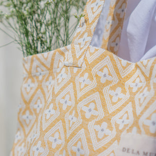 Nahaufnahme der Stofftasche Shopper L in der Farbe Sunny Geometric von De La Mur, zeigt das gewebte Muster und das Markenlabel.