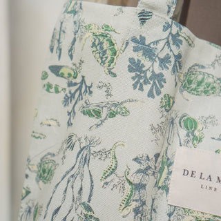 Detailaufnahme der Stofftasche Shopper M in der Farbe Turtle Cove von De La Mur, die den Stoff und das Logo zeigt.