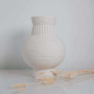 Große Vase Athens von der Marke Claet, handgefertigt mit feinen Rillenstrukturen in elegantem Weiß. Modernes und minimalistisches Design, perfekt als Dekorationsstück oder für Trockenblumen, präsentiert mit zarten Pampasgras-Details.