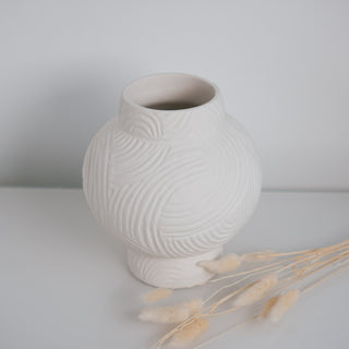 Kleine Vase Athens von der Marke Claet, handgefertigt mit feinen Rillenstrukturen in elegantem Weiß. Modernes und minimalistisches Design, perfekt als Dekorationsstück oder für Trockenblumen, präsentiert mit zarten Pampasgras-Details.