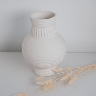 Große Vase Athens von der Marke Claet, handgefertigt mit feinen Rillenstrukturen in elegantem Weiß. Modernes und minimalistisches Design, perfekt als Dekorationsstück oder für Trockenblumen, präsentiert mit zarten Pampasgras-Details.