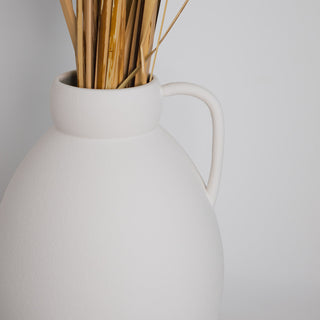Minimalistische Vase Ghara groß, handgefertigt von Claet. Elegantes Design mit sanft gerundeter Form und praktischem Griff, perfekt für zeitgenössische Dekorationen oder Trockenblumenarrangements. Gefertigt in hochwertigem, strukturiertem Weiß.