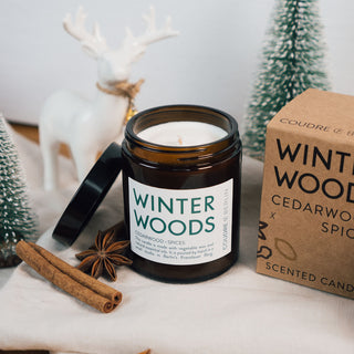 Vegane Duftkerze Winter Woods von Coudre Berlin, präsentiert mit natürlicher Verpackung. Enthält Noten von Zedernholz und Gewürzen, handgegossen in Berlin. Nachhaltig, stilvoll und perfekt für die Winterzeit, dekoriert mit weihnachtlichen Akzenten wie Zimt, roten Beeren und Tannenzweigen.